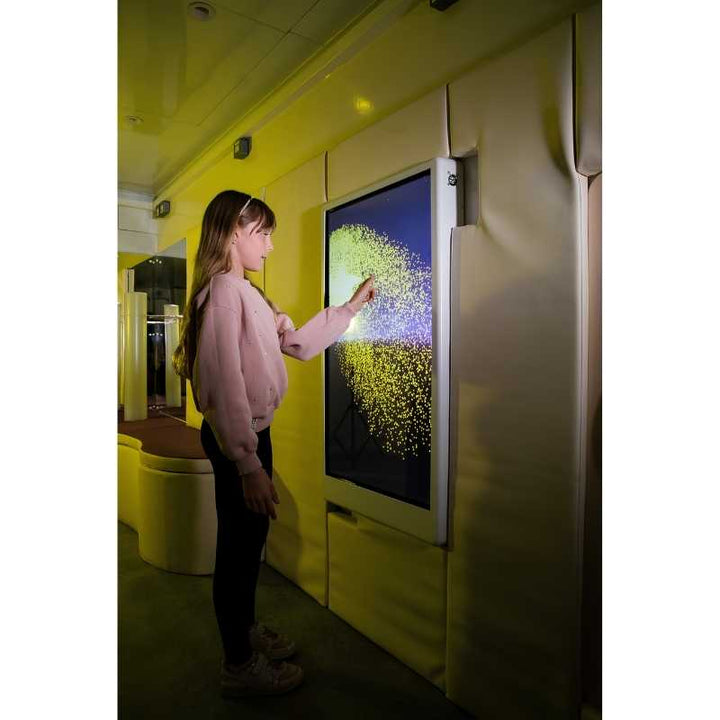 Side view of a child engaging with the Experia Intelli Panel Particle interactive sensory panel in a yellow-lit room