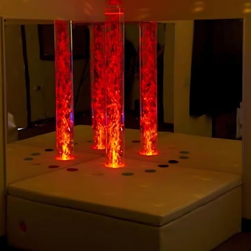Experia Interactive Bubble Tube Corner full room view with bubble tube glowing in red light, showing the complete interactive LED bubble tube sensory corner with acrylic mirrors