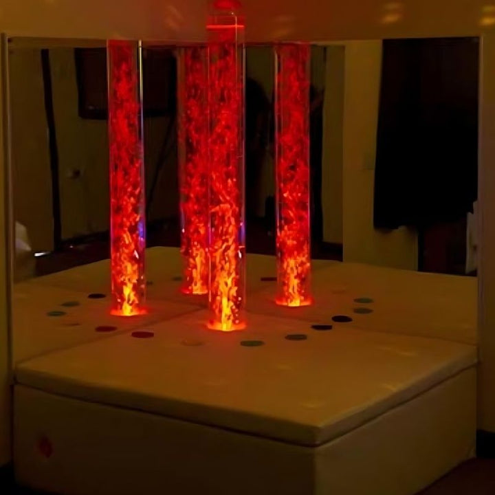 Experia Interactive Bubble Tube Corner full room view with bubble tube glowing in red light, showing the complete interactive LED bubble tube sensory corner with acrylic mirrors