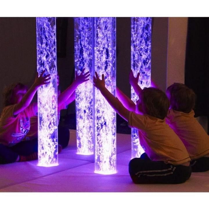 Child actively engaging with the Experia IRiS LED Bubble Tube in a sensory room, showing interactive colour-controlled bubble tube play using an IRiS Talker controller