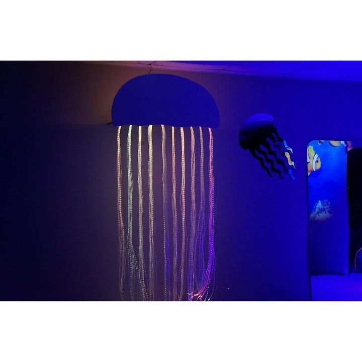 Experia Calming Fiber Optic Jellyfish in purple and blue light, landscape view showing the colour-shifting underwater fibre optic sensory display within the themed room environment