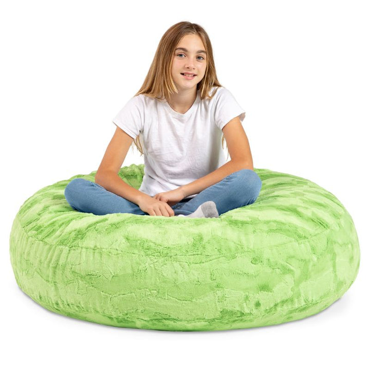A child sitting cross-legged on the Jaxx Cocoon Fur faux fur bean bag chair in Green, a crash pad for kids at play