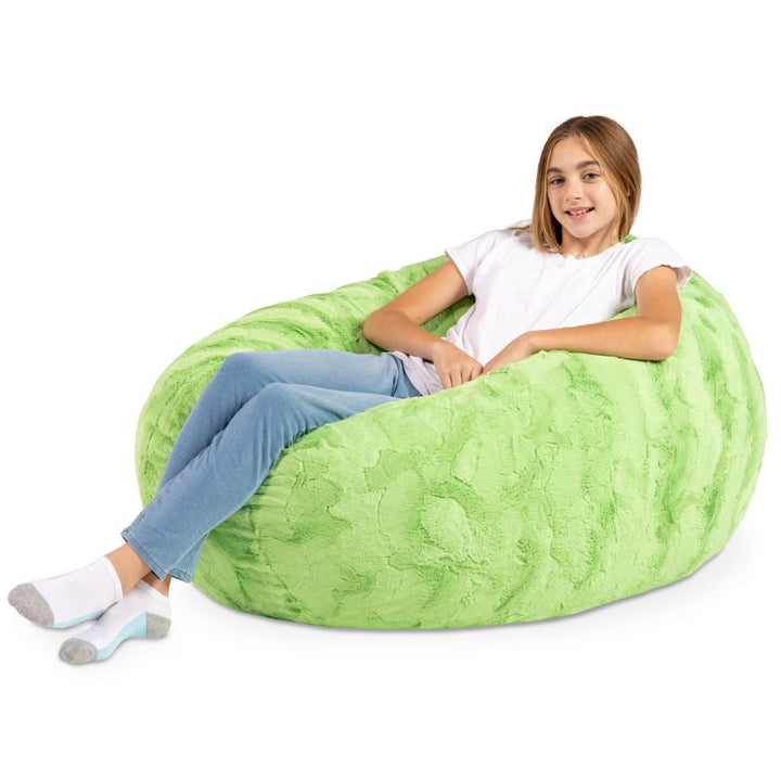 A child reclining into the Jaxx Cocoon Fur faux fur bean bag chair in Green, molded into a cozy lounging position