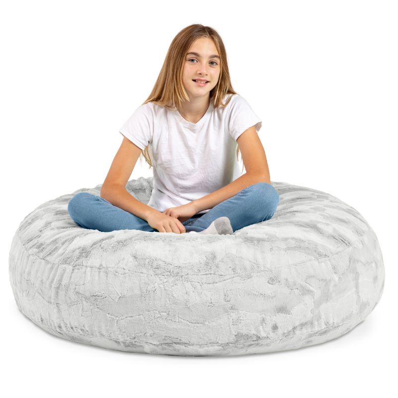 A child sitting cross-legged on the Jaxx Cocoon Fur faux fur bean bag chair in Grey, a neutral seat for kids in any room