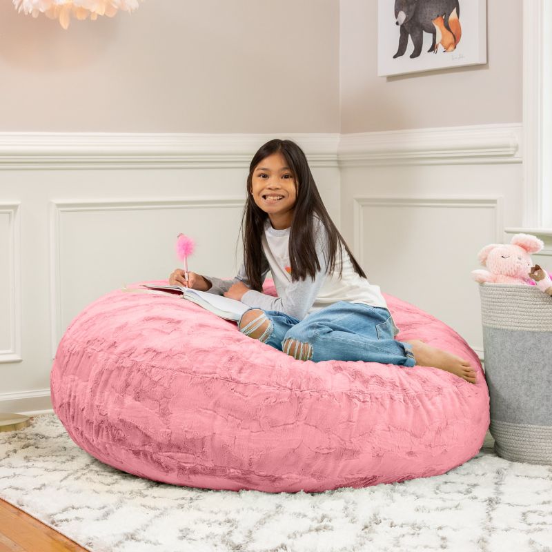 A child reading on the Jaxx Cocoon Fur faux fur bean bag chair in Pink, styled in a bedroom as everyday kids' seating