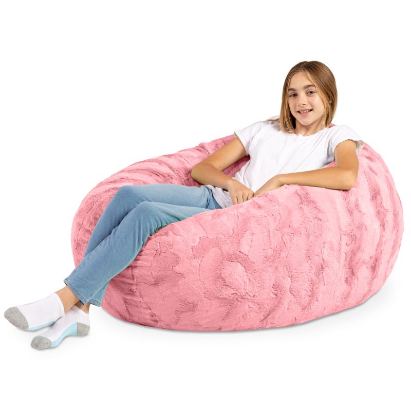 A child reclining into the Jaxx Cocoon Fur faux fur bean bag chair in Pink, molded into a supportive lounging position