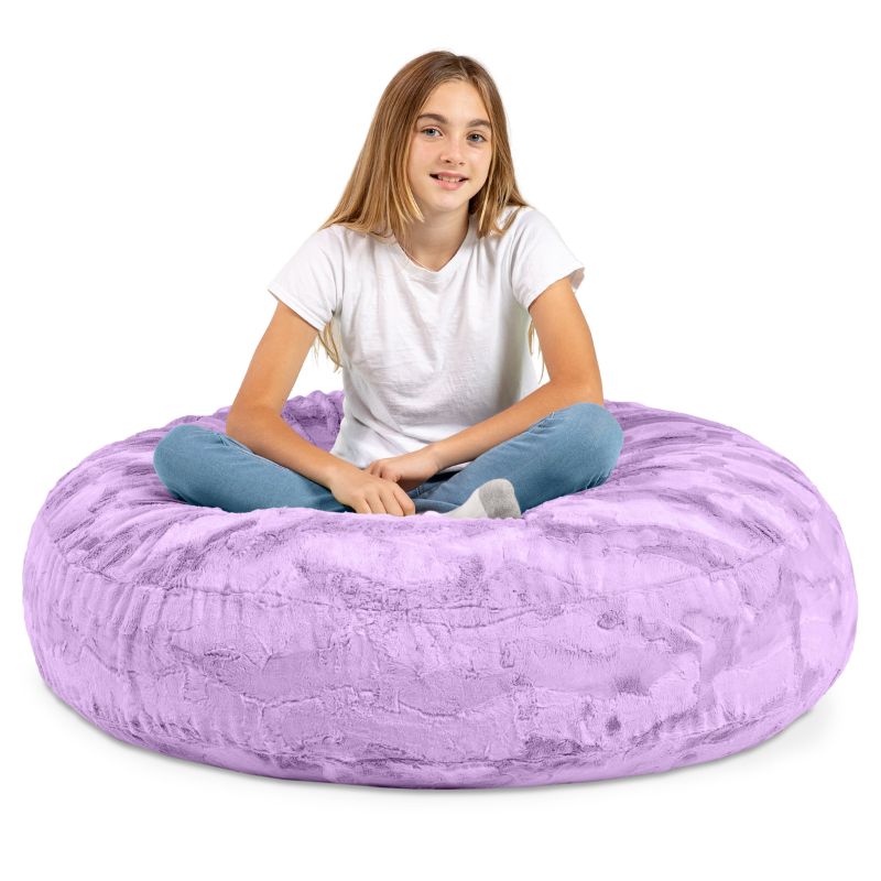 A child sitting cross-legged on the Jaxx Cocoon Fur faux fur bean bag chair in Purple, classroom seating for kids