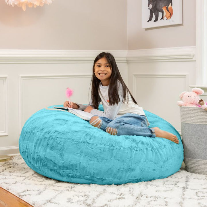 A child reading on the Jaxx Cocoon Fur faux fur bean bag chair in Teal, styled in a bedroom as everyday kids' seating