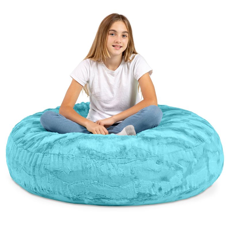 A child sitting cross-legged on the Jaxx Cocoon Fur faux fur bean bag chair in Teal, sensory seating for kids at home