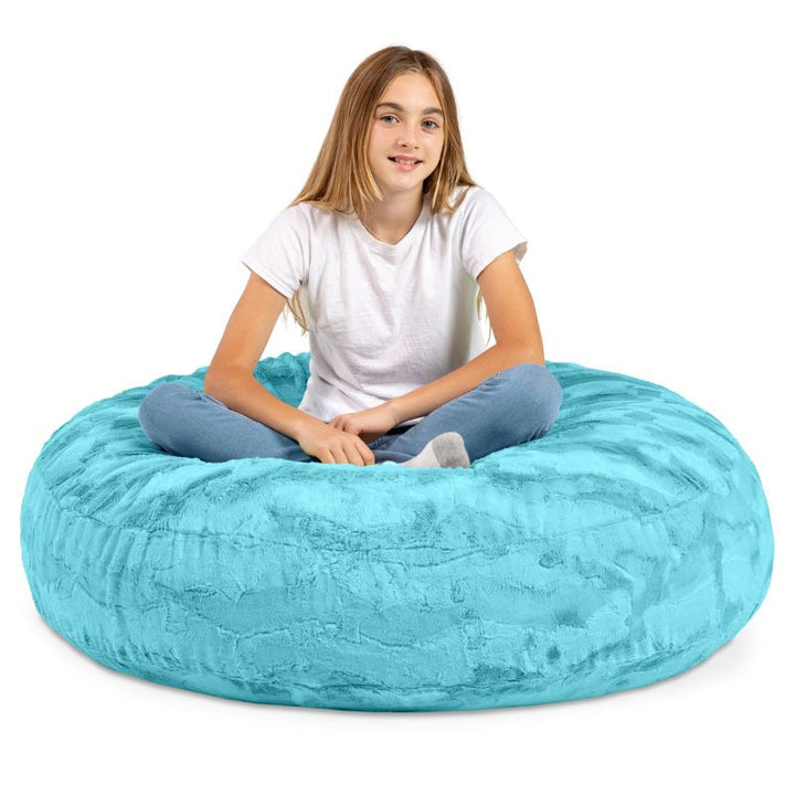 A child sitting cross-legged on the Jaxx Cocoon Fur faux fur bean bag chair in Teal, sensory seating for kids at home