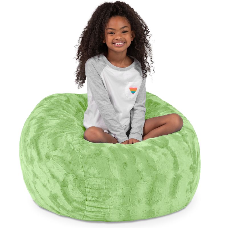 Child seated in the Jaxx Saxx faux fur bean bag chair in Green, a soft tactile sensory seat for kids