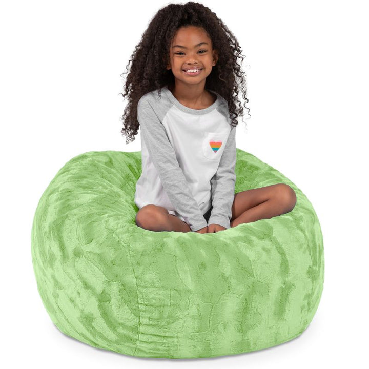Child seated in the Jaxx Saxx faux fur bean bag chair in Green, a soft tactile sensory seat for kids