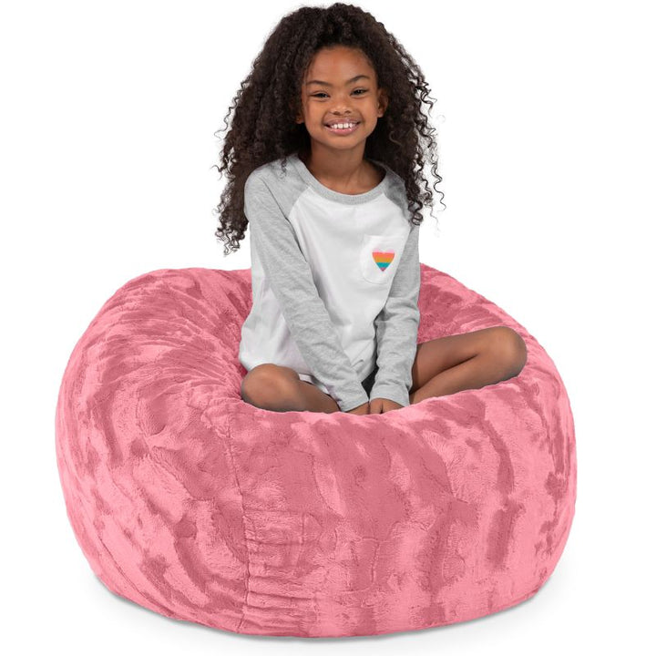 Child seated in the Jaxx Saxx faux fur bean bag chair in Pink, a plush tactile sensory seat for kids