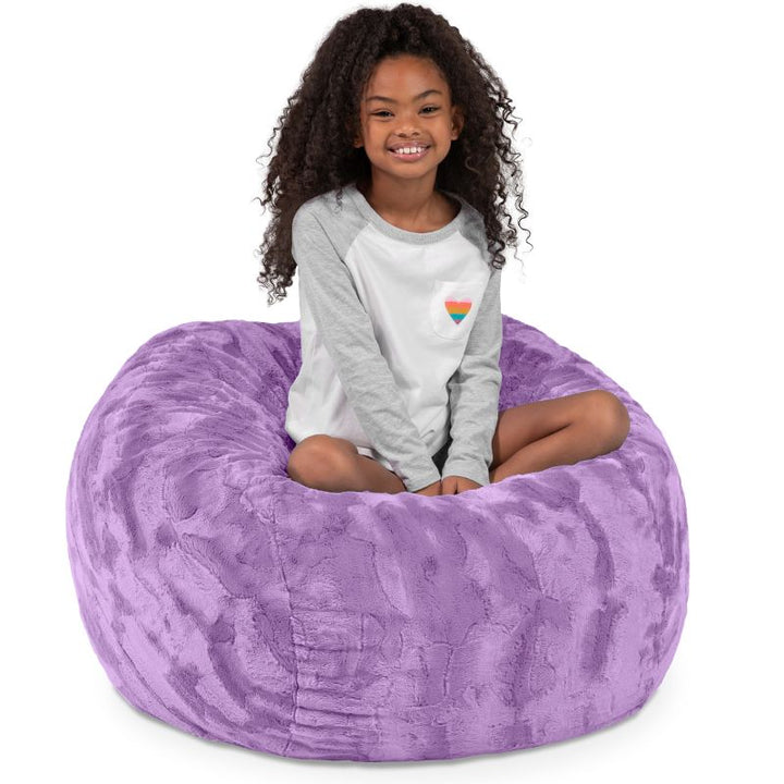 Child seated in the Jaxx Saxx faux fur bean bag chair in Purple, a soft tactile sensory seat for kids
