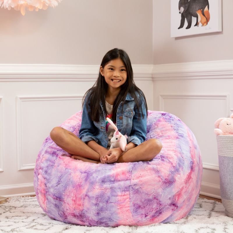 Girl sitting on the Jaxx Saxx faux fur bean bag chair in Unicorn in a cozy bedroom, a tactile sensory seat for kids