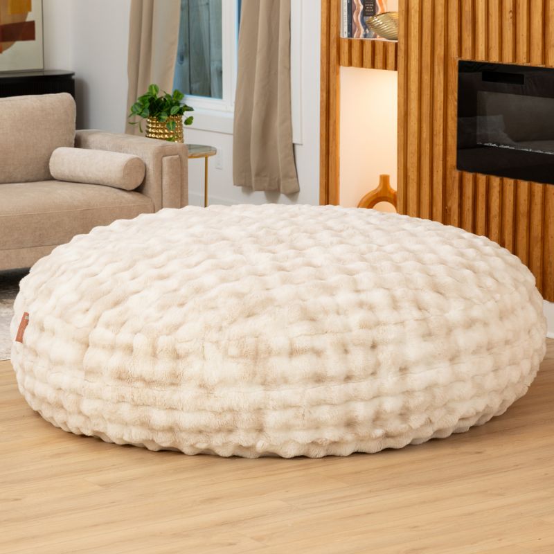 Big Snuggler by Raven-Symone faux fur bean bag lounger in Phantom Cream styled in a living room for cozy lounging