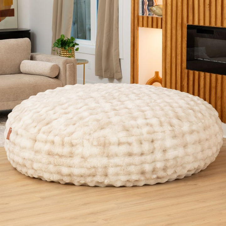 Big Snuggler by Raven-Symone faux fur bean bag lounger in Phantom Cream styled in a living room for cozy lounging