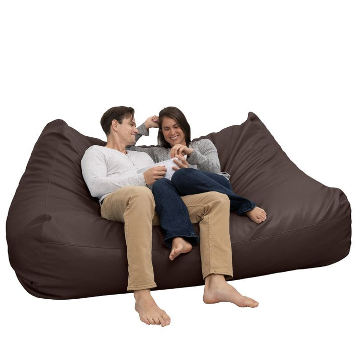 Two people relaxing on the Jaxx Lozia faux leather loveseat in chocolate, easy-clean waiting room seating