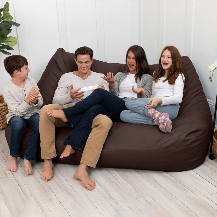 A family sharing the Jaxx Lozia faux leather loveseat in chocolate, easy-clean waiting room seating