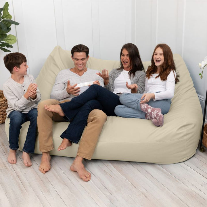 A family sharing the Jaxx Lozia faux leather loveseat in natural beige, classroom soft seating