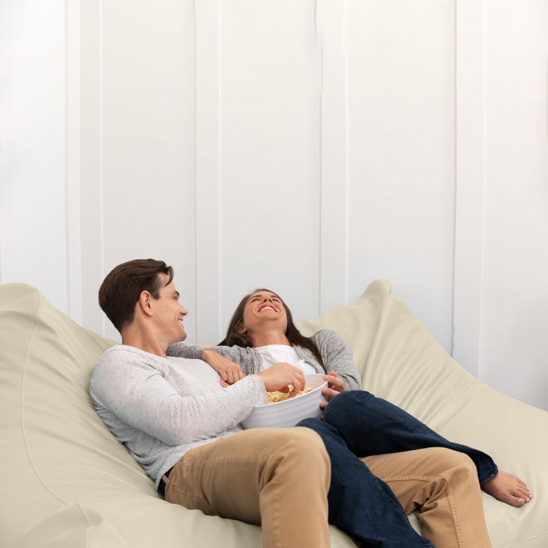 A couple sharing popcorn on the Jaxx Lozia faux leather loveseat in natural beige, classroom soft seating
