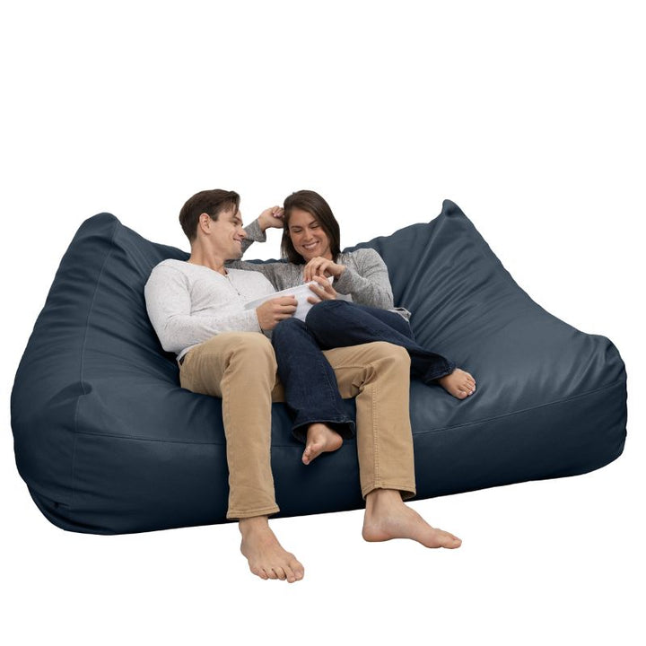 Two people relaxing on the Jaxx Lozia faux leather loveseat in oxford blue, two-seat waiting room seating