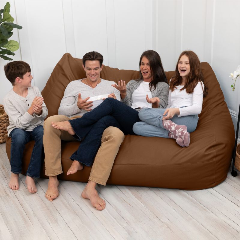 A family sharing the Jaxx Lozia faux leather loveseat in walnut, easy-clean soft seating for reception areas