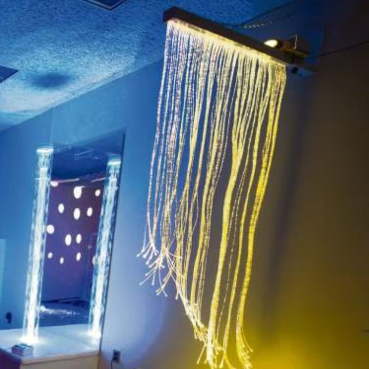 TFH Fiber Optic Curtain mounted on an adjustable wall bracket, glowing gold in a calming sensory room setting