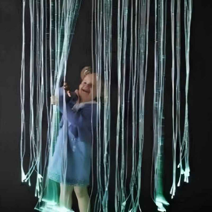A person standing within the TFH Fibre Optic Curtain's glowing green strands, immersed in the calming visual effect of this sensory light curtain