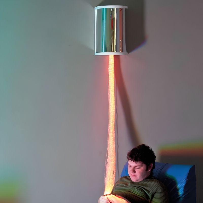 TFH Fibre Optic Wall Sconce mounted above a seated person, glowing orange fiber optic tails hanging down for calming sensory room light play