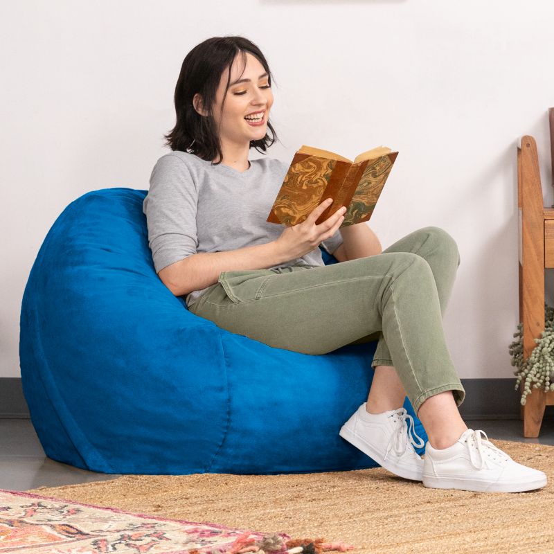 Smiling reader relaxing in a Blueberry microsuede Jaxx Saxx 3ft foam bean bag chair, a round bean bag chair for quiet time