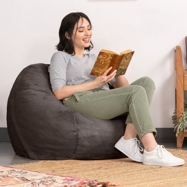 Reader settled into a Charcoal microsuede Jaxx Saxx 3ft foam bean bag chair, showing how the foam fill cradles the back
