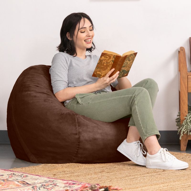 Reader relaxing in a Chocolate microsuede Jaxx Saxx 3ft foam bean bag chair, a cozy round seat for reading and decompressing