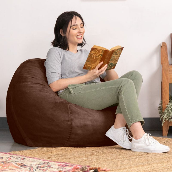 Reader relaxing in a Chocolate microsuede Jaxx Saxx 3ft foam bean bag chair, a cozy round seat for reading and decompressing