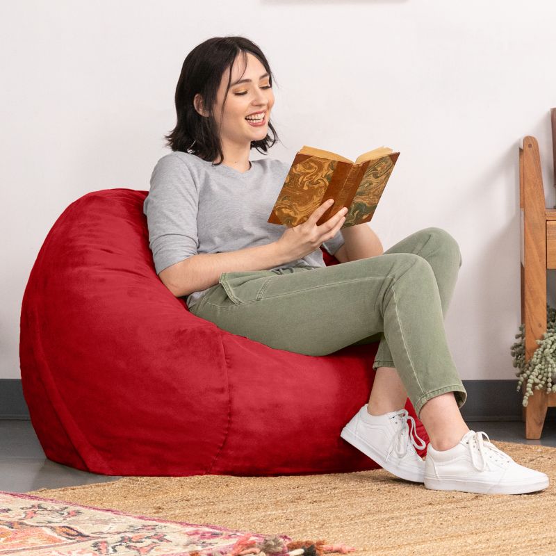 Woman laughing over a book in a Cinnabar red microsuede Jaxx Saxx 3ft foam bean bag chair, soft sensory seating