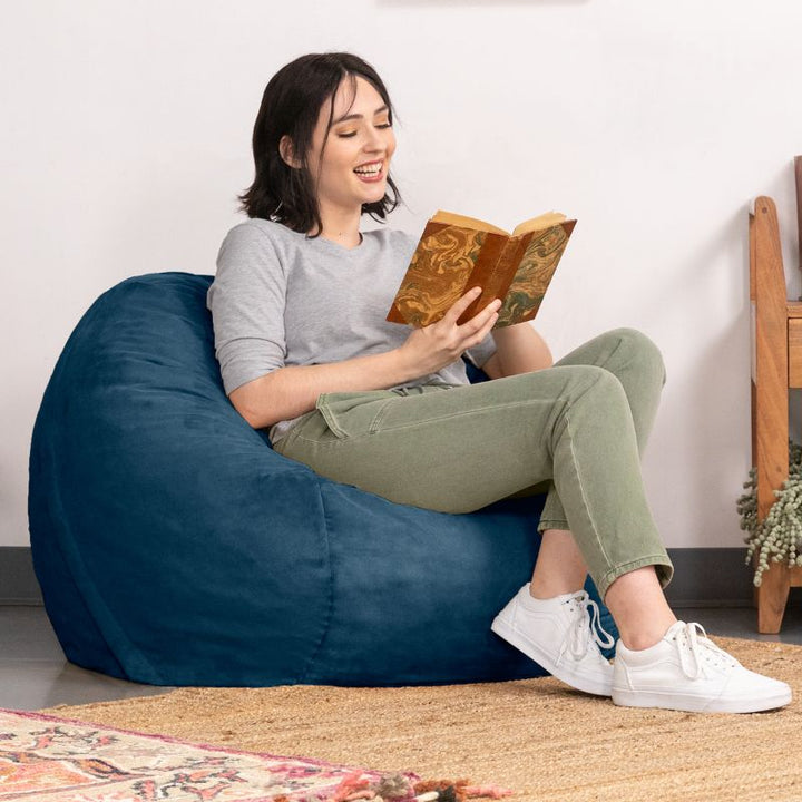 Woman reading in a Navy microsuede Jaxx Saxx 3ft foam bean bag chair, a round bean bag chair with a removable washable cover