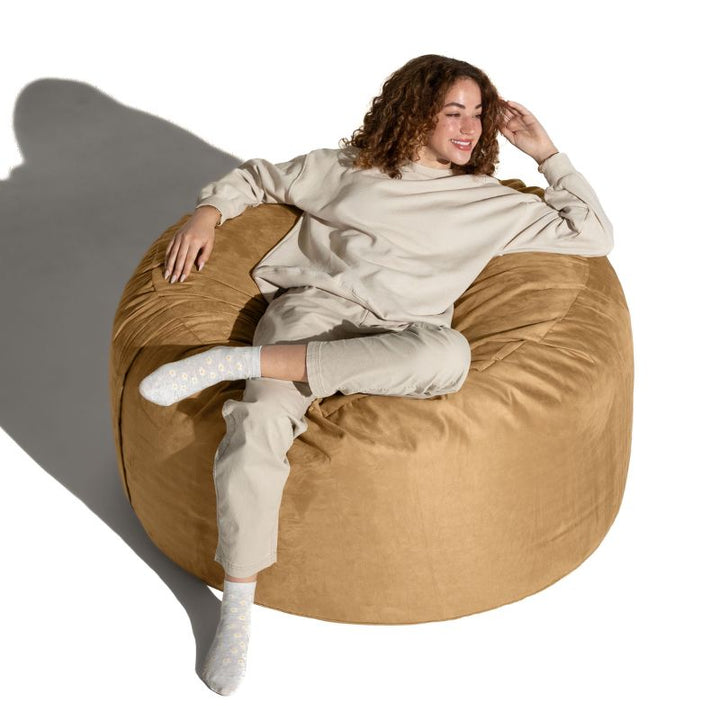 Overhead view of a woman relaxing on a Camel microsuede Jaxx Saxx 4ft foam bean bag chair, cozy seating for teens and adults