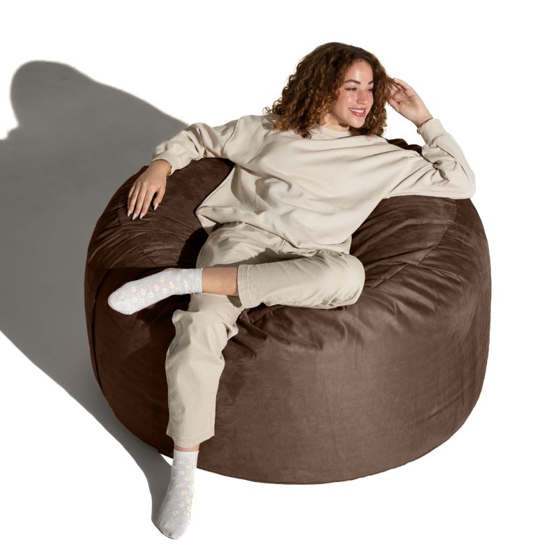 Smiling woman lounging on a Chocolate microsuede Jaxx Saxx 4ft foam bean bag chair, a supportive round bean bag chair for downtime