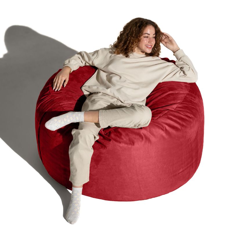 Overhead view of a woman relaxing on a Cinnabar red microsuede Jaxx Saxx 4ft foam bean bag chair, soft sensory seating for adults