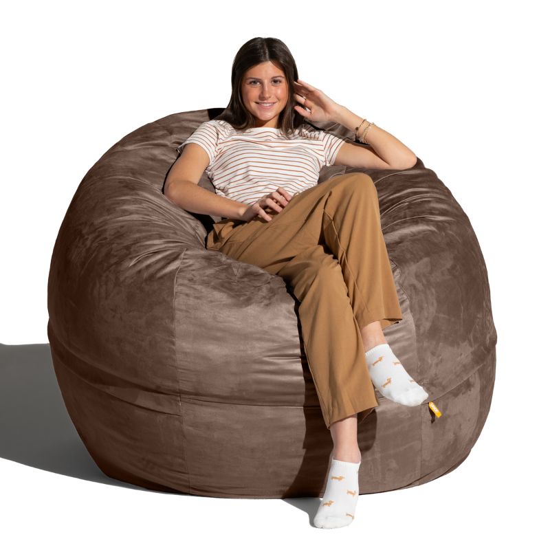 Young woman settled into a Chocolate microsuede Jaxx Saxx 5ft foam bean bag chair, a supportive seat filled with foam micro-cushions
