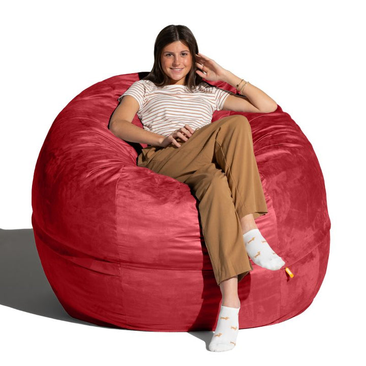 Young woman relaxing in a Cinnabar red microsuede Jaxx Saxx 5ft foam bean bag chair, roomy sensory seating for shared spaces