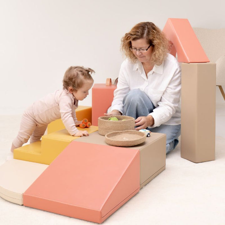 Close-up of a baby climbing onto the IGLU Foam Play Set - Creativity platform, soft foam climbing blocks for early mobility