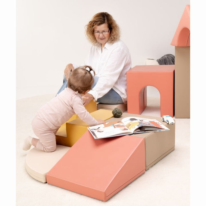 Baby kneeling at the IGLU Foam Play Set - Creativity steps beside a picture book, showing quiet baby soft play with a caregiver