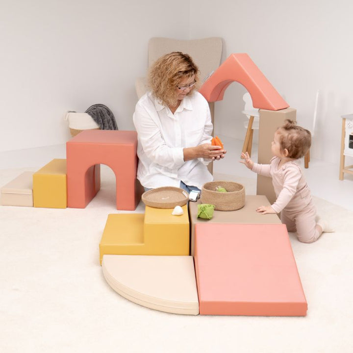 Baby pulling up to stand at the IGLU Foam Play Set - Creativity platform during hands-on sensory play with a caregiver