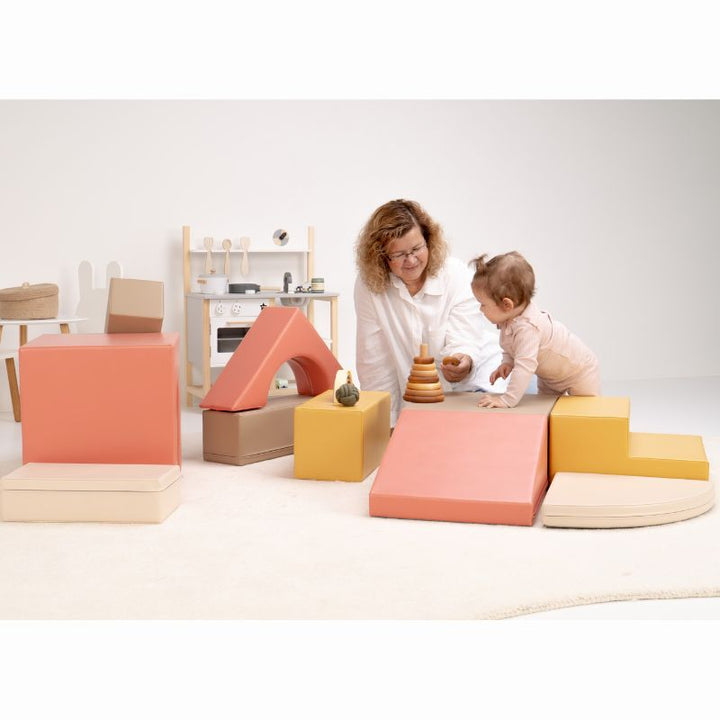 Baby crawling onto the IGLU Foam Play Set - Creativity platform beside a ring stacker, with the full modular soft play set nearby