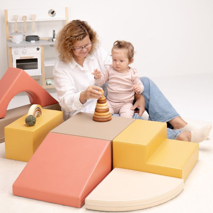 Caregiver and baby sitting together on the IGLU Foam Play Set - Creativity, stacking wooden rings during fine motor baby soft play