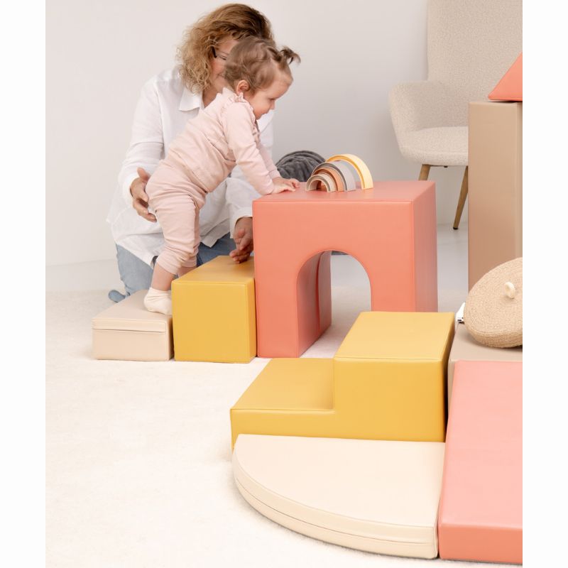 Side view of a toddler climbing the step shapes of the IGLU Foam Play Set - Creativity, soft foam climbing blocks for early mobility