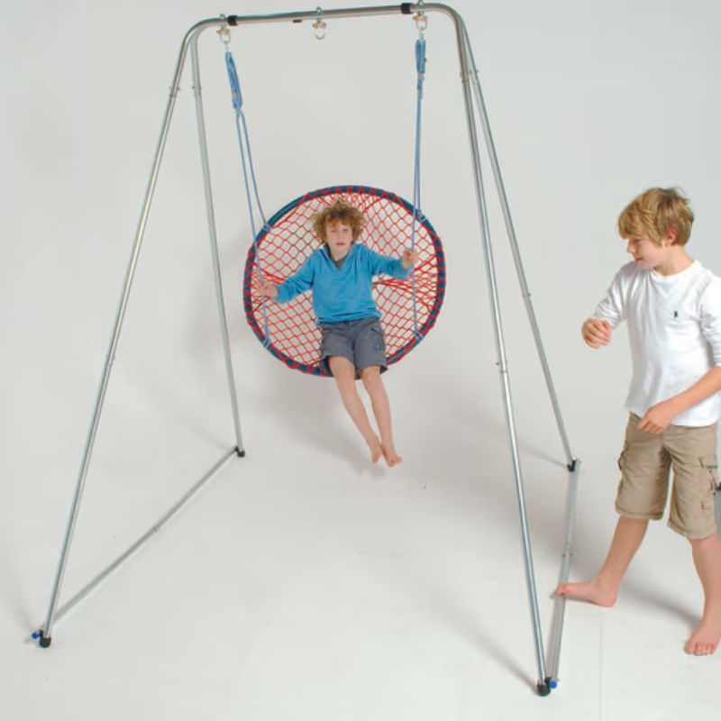 A child swinging in a net seat on the TFH Foldaway Swing Frame, a portable sensory swing stand for vestibular play