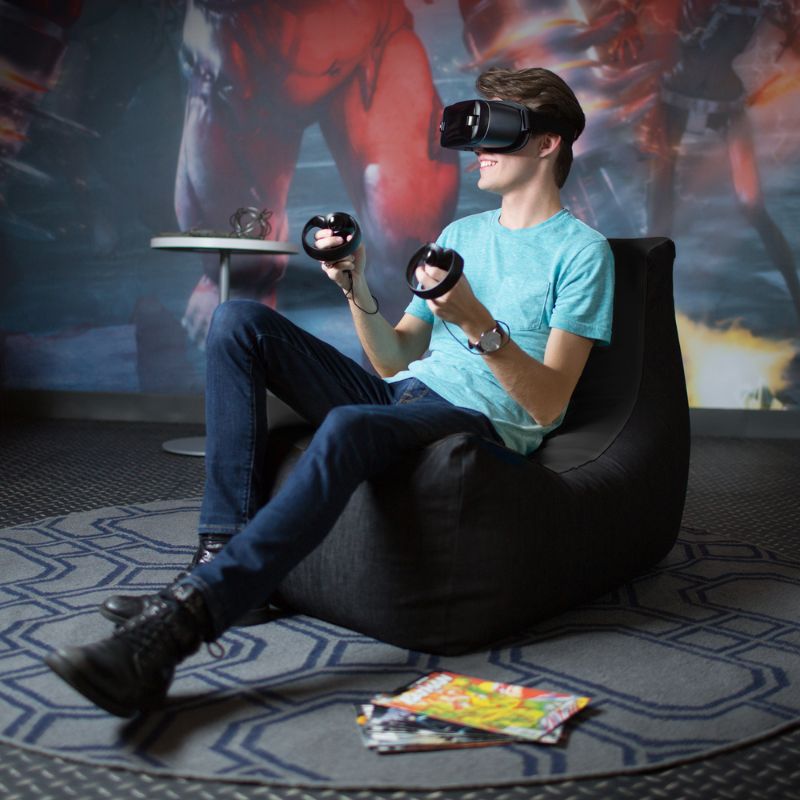 A teen uses a VR headset while seated in the Jaxx Pixel gaming bean bag chair in black, a durable seat for game rooms