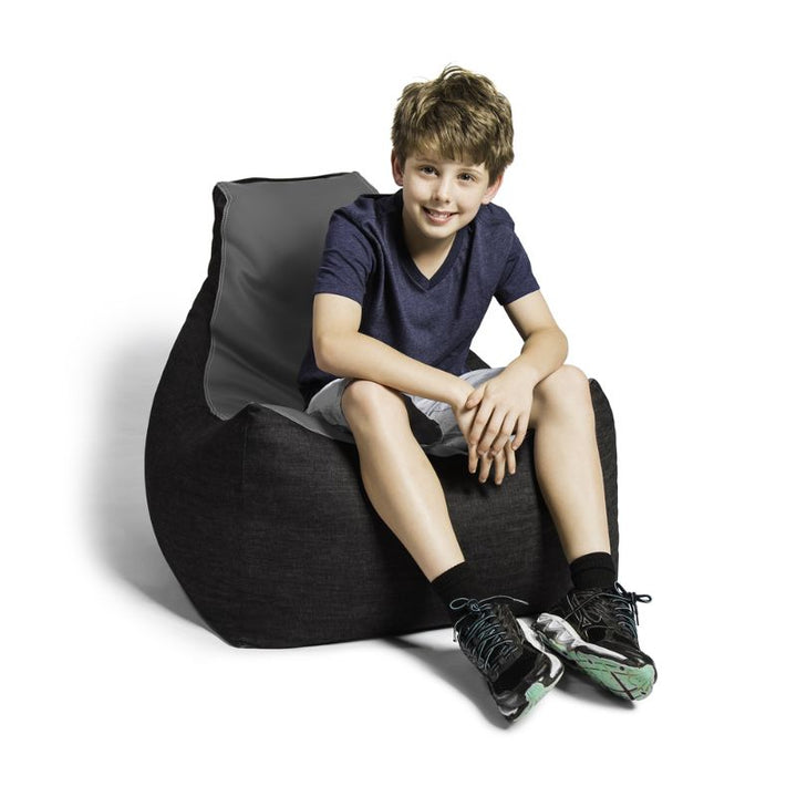 A boy sits comfortably in the Jaxx Pixel gaming bean bag chair in charcoal, a durable library seating option